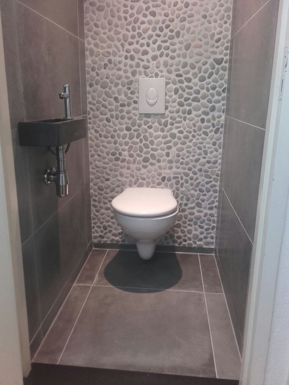 WC met tegelvloer en kiezelwand